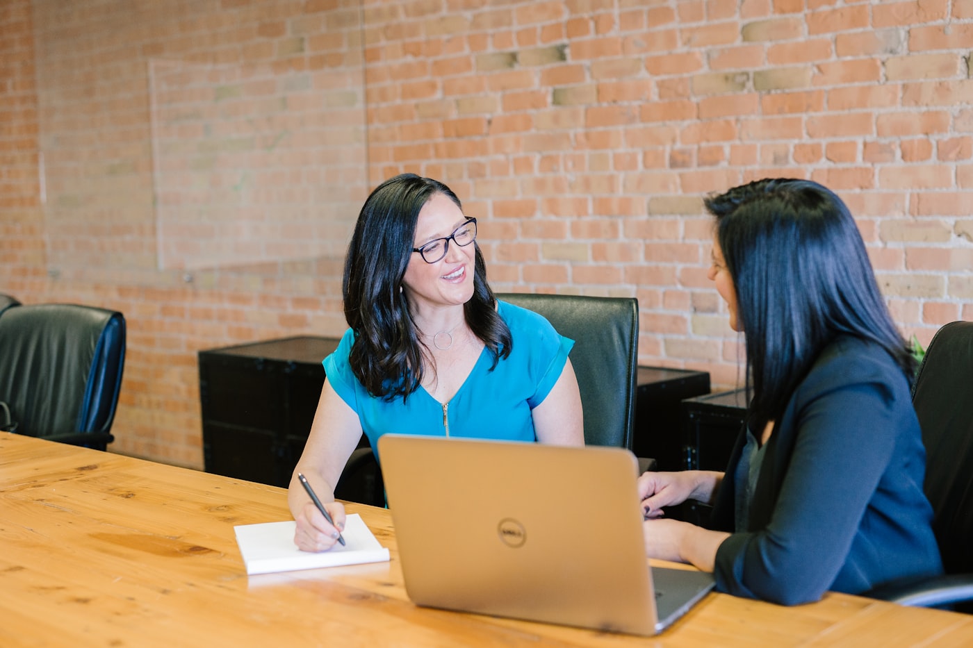 Two people in conversation across a table, one taking notes